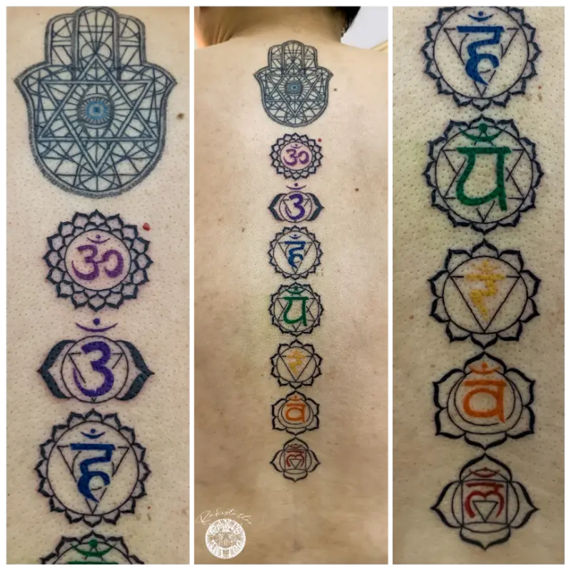 colored chakra symbols and hamsa hand tattoo running down the spine