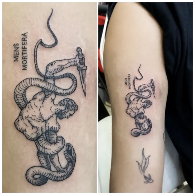 black and grey illustrative snake coiled around a figure with dagger and 'Mens Mortifera' lettering tattoo on upper arm